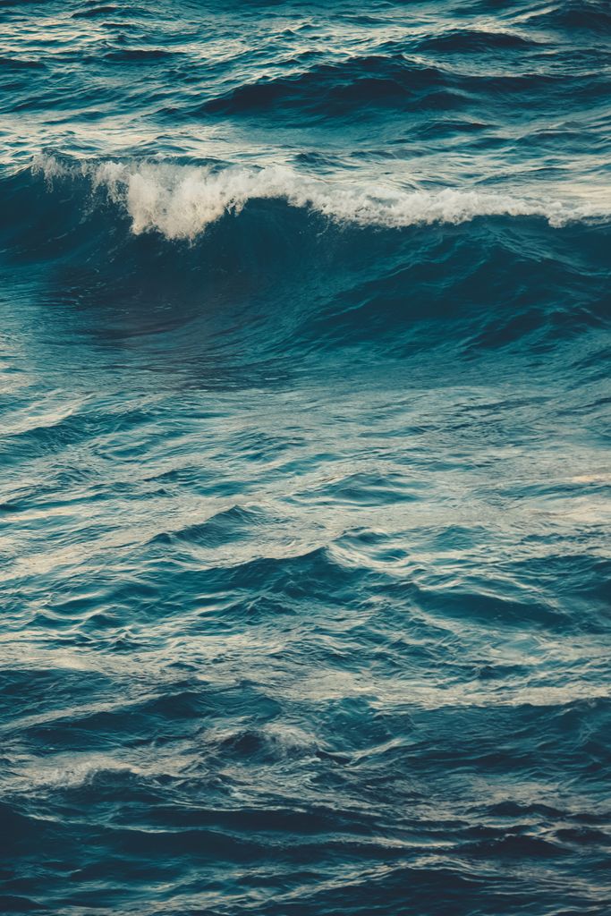 Vibrant ocean waves rolling on a windy day, captured in a vertical shot. Perfect for nature themes.